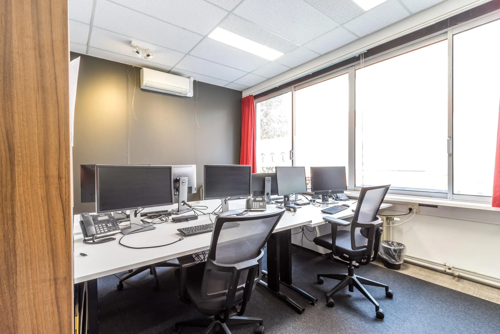 Kantoorruimte aan de Jan van Eycklaan met meerdere werkplekken, bureaustoelen en computerschermen.